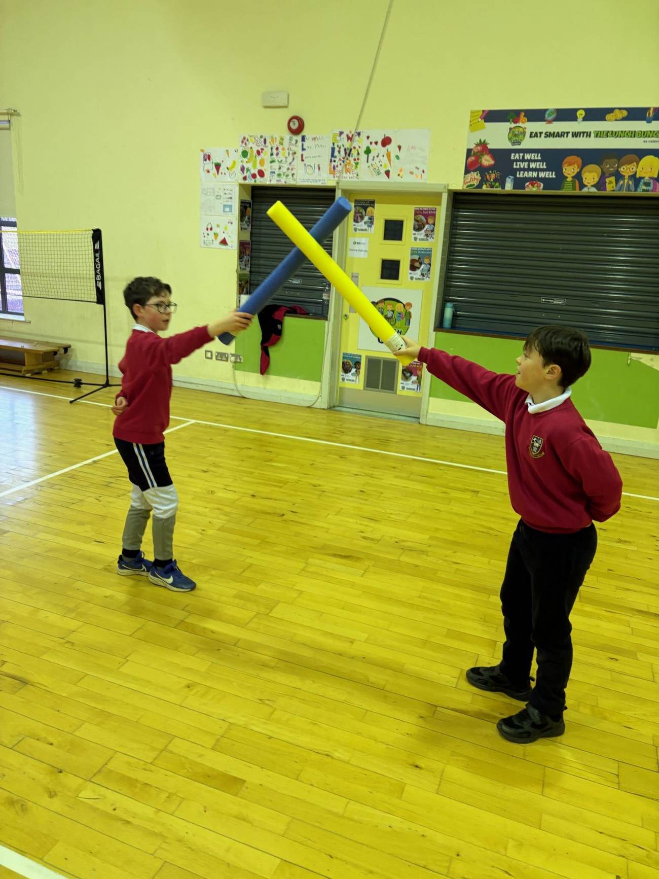 Children taking part in a movement-based PE activity using pool noodles