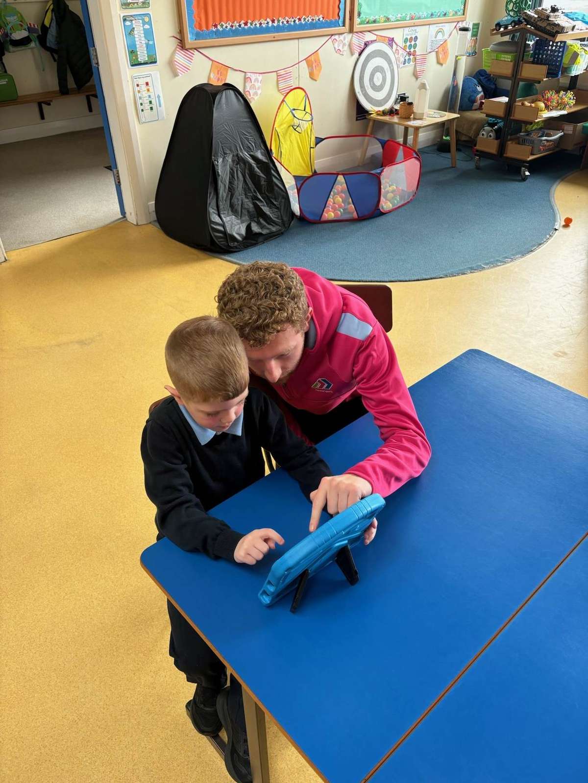 Adam working one-to-one with a child using a tablet during a STEM activity