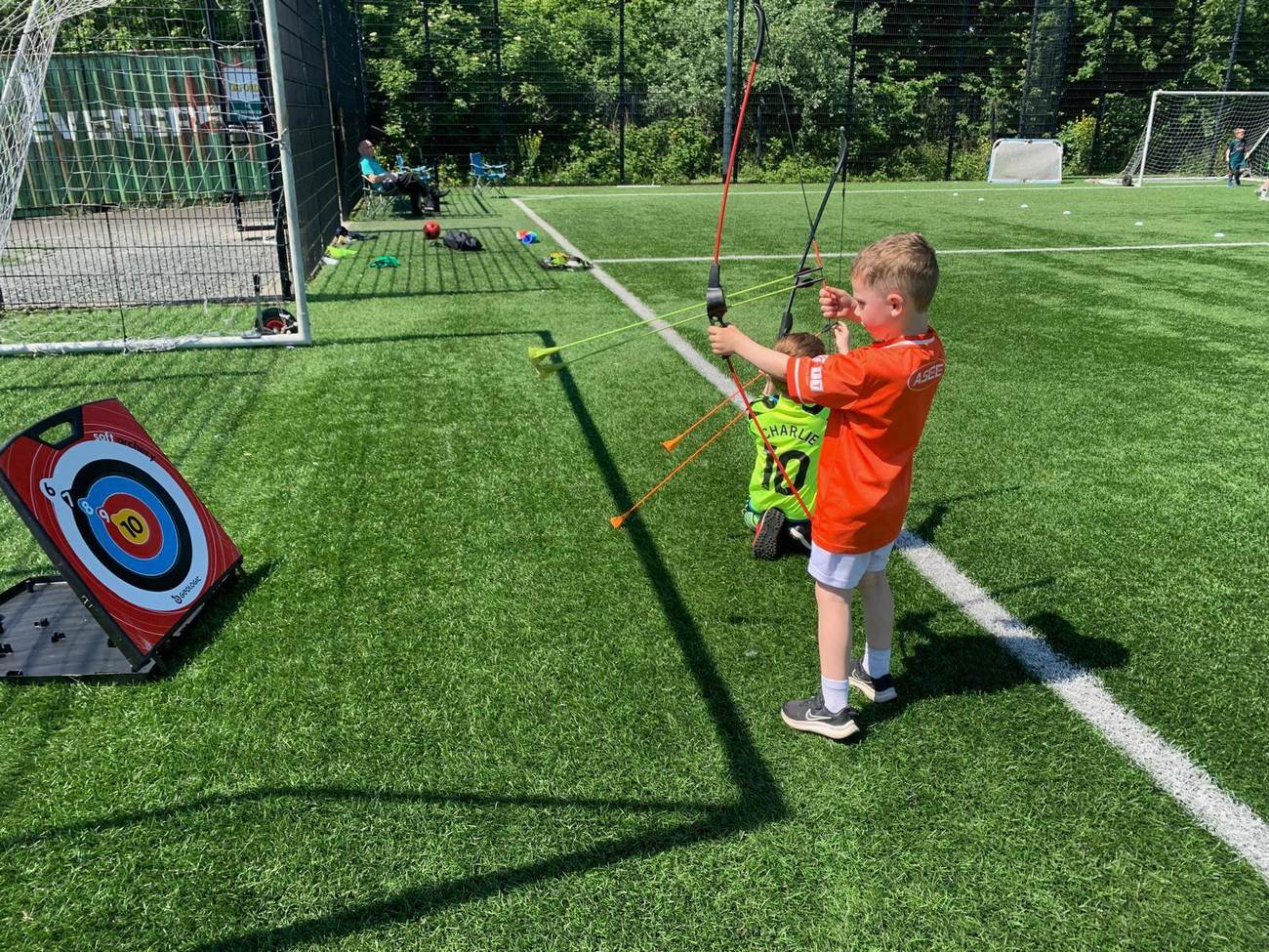 Child taking aim with an archery bow on the astro pitch during an Elevate Sports holiday camp