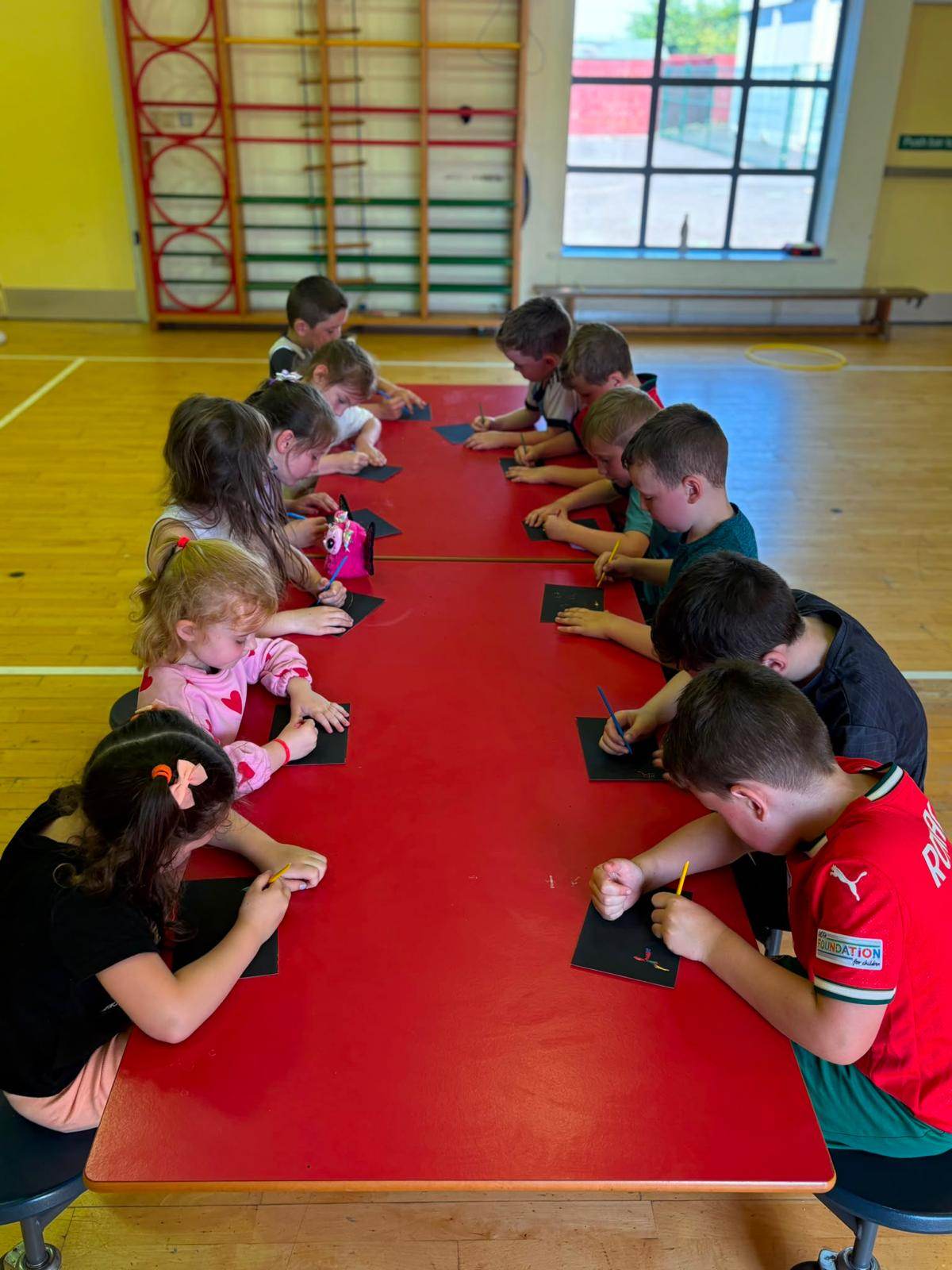 Children doing scratch art crafts together at a table during an Elevate Sports holiday camp