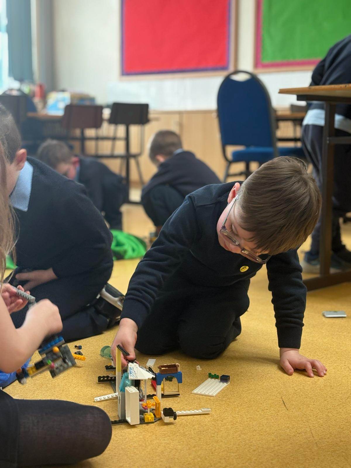 A child focused on building with LEGO on the floor during an Elevate360 session