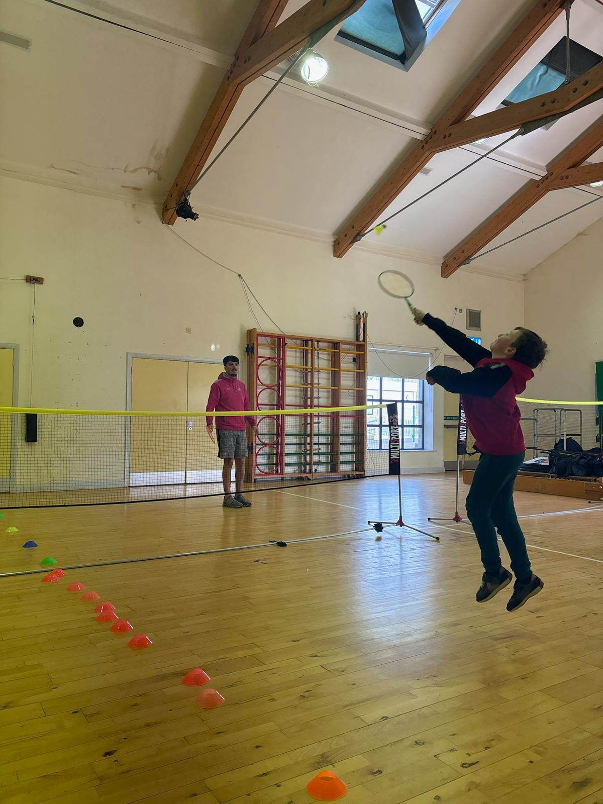 A child jumping to smash a badminton shuttle during an Elevate FUNdamentals session