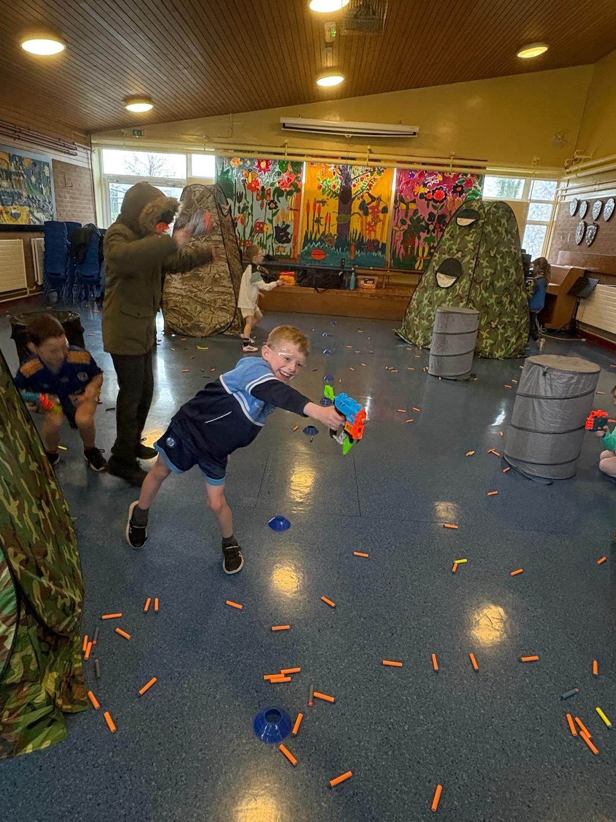 Children playing in a Nerf battle arena with camouflage tents during an Elevate Sports birthday party