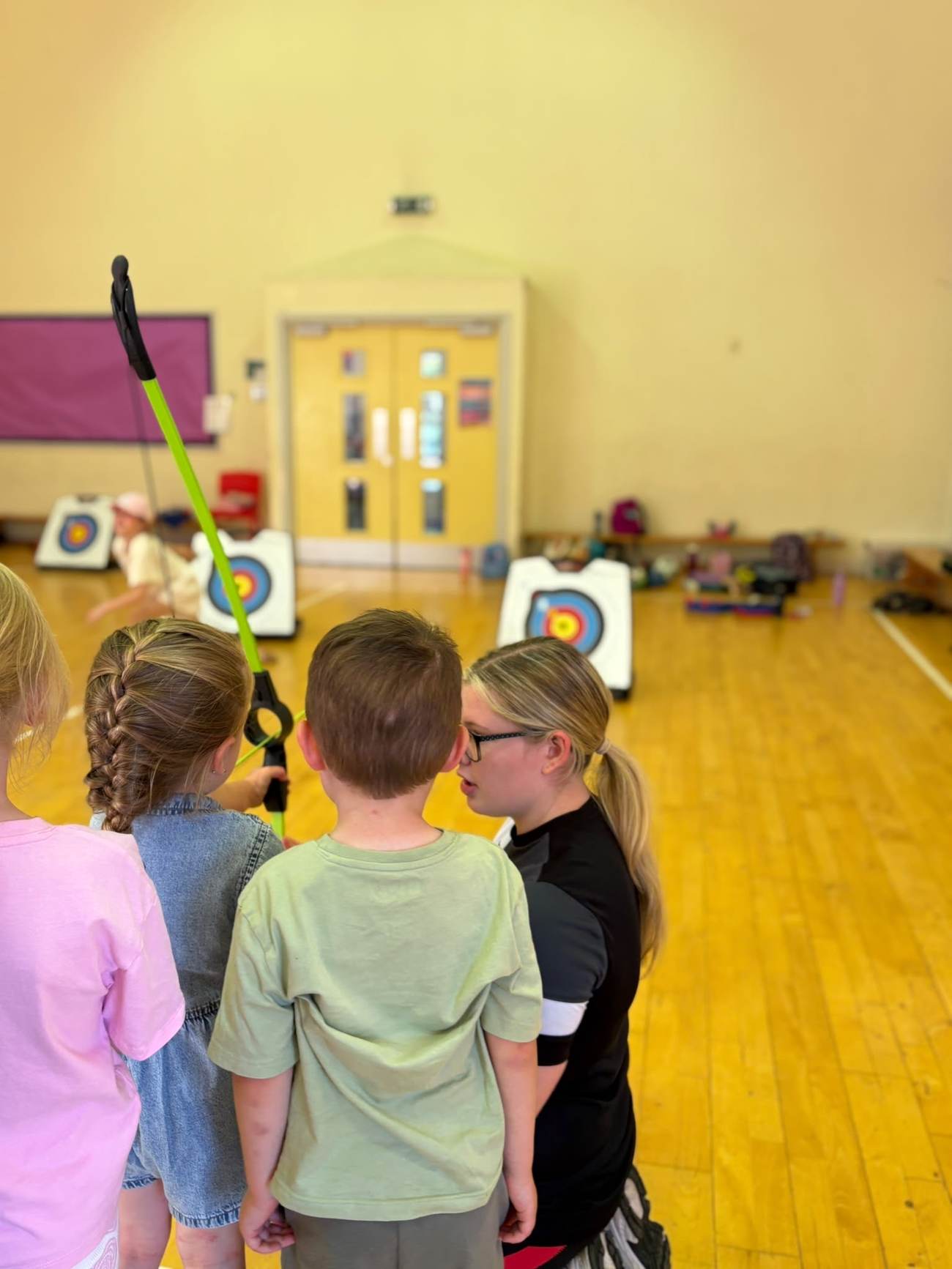 Children taking part in an archery lesson with a coach during an Elevate Sports holiday camp