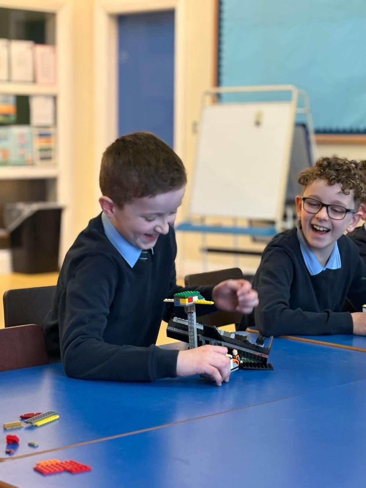 Two boys laughing together over a LEGO build during an Elevate Sports after-school club
