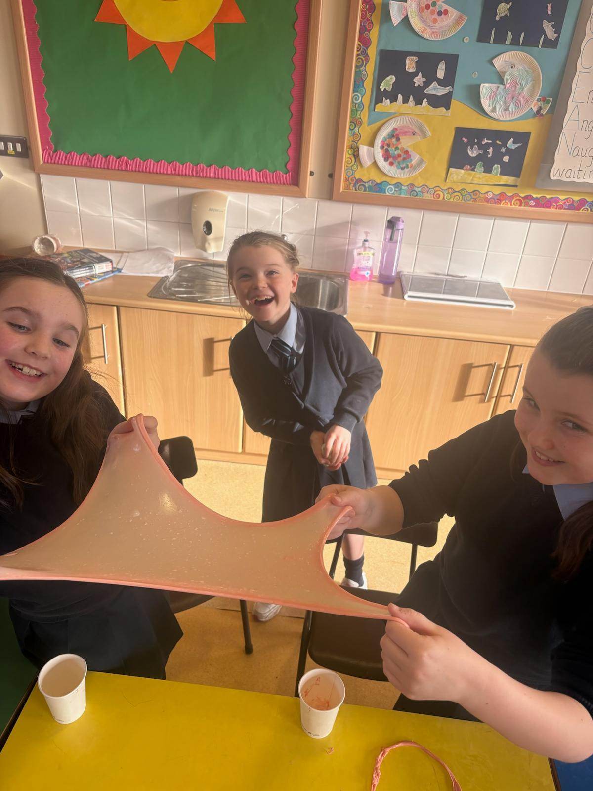 Children stretching slime during a STEM club session