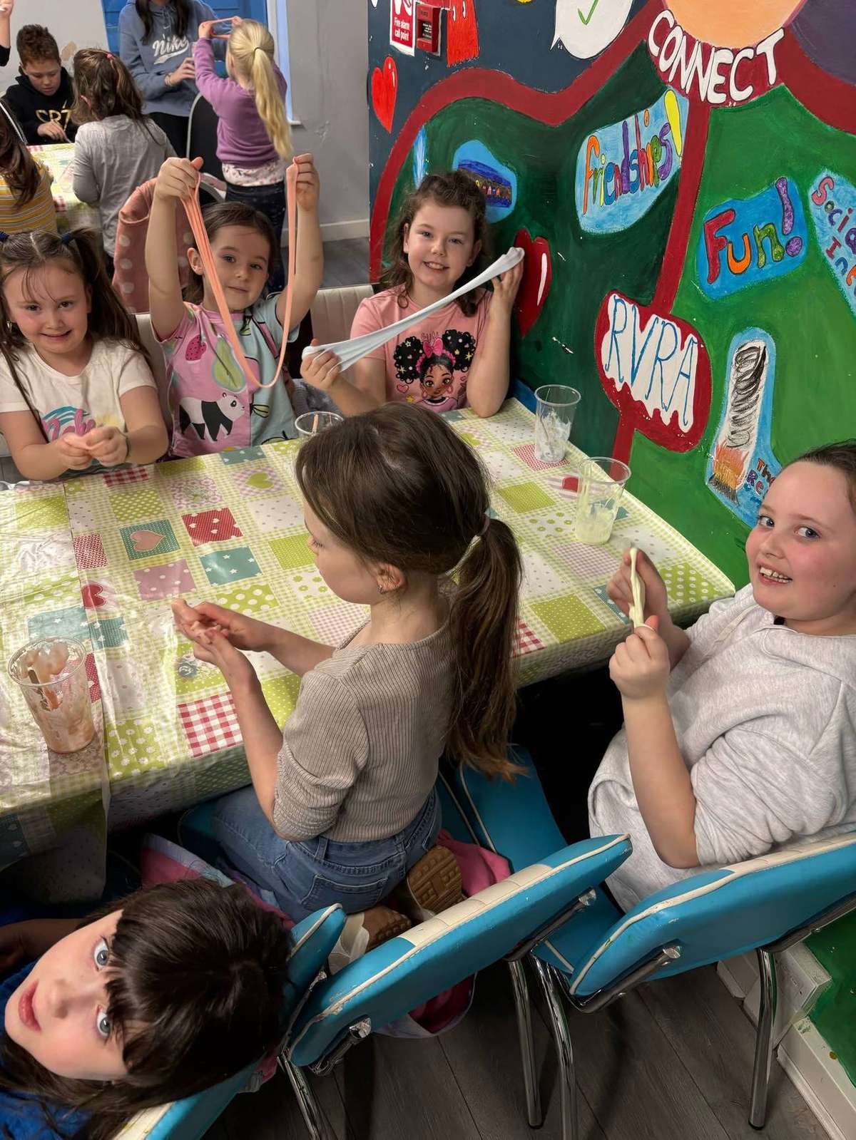 A group of children making slime together around a table during an Elevate Sports community activity